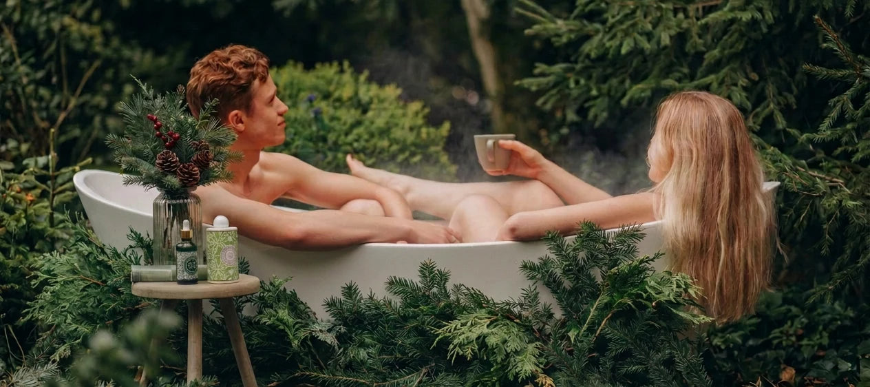 A couple relaxing in a bath surrounded by English countryside greenery